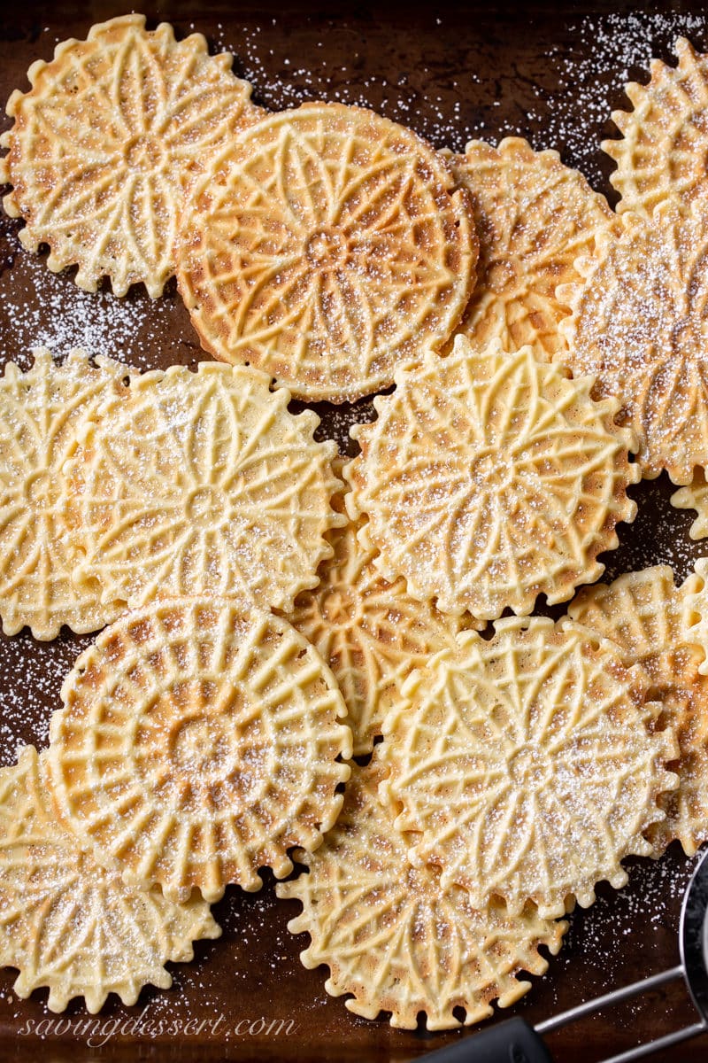 A cookie sheet covered in pizzelle cookies dusted with powdered sugar