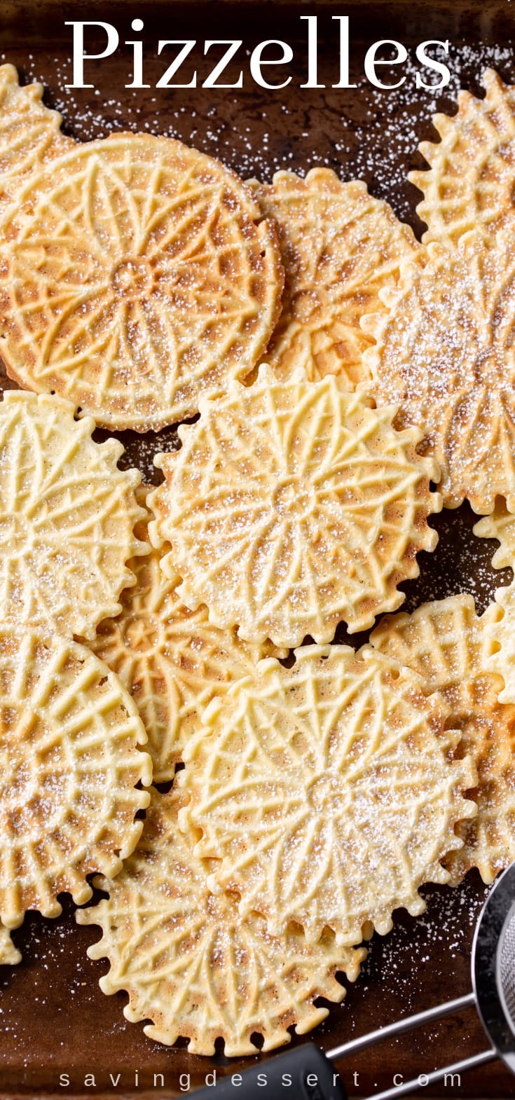 A baking tray covered with pizzelle cookies dusted with powdered sugar