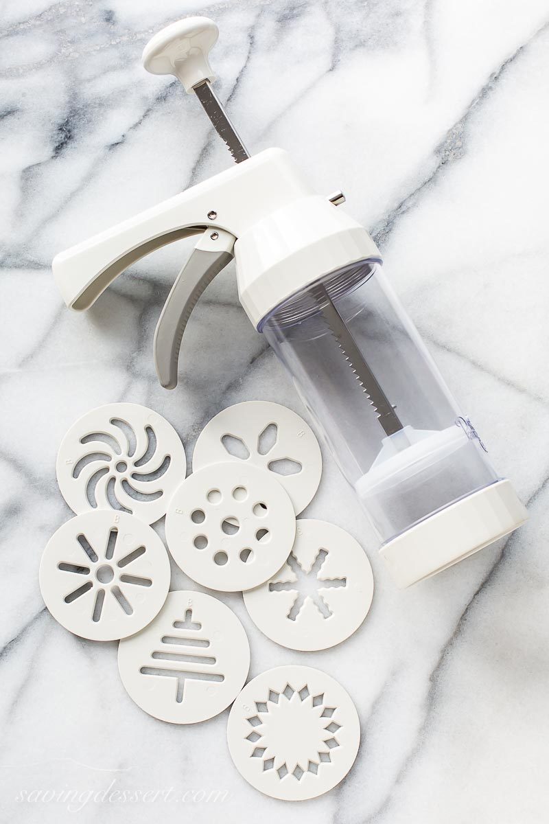 A cookie press with a variety of discs used in making Spritz cookies