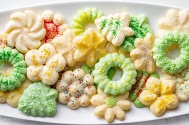 A platter of colorful Spritz Cookies made using a cookie press