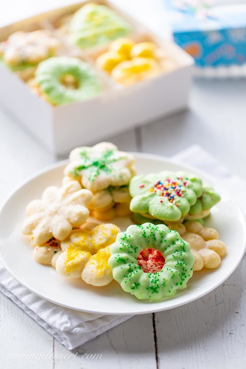 A plate and box of holiday Spritz cookies decorated in sprinkles