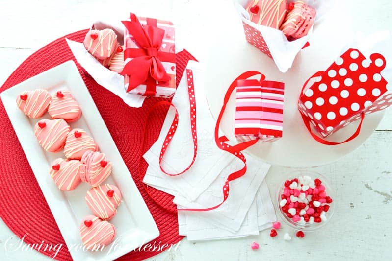 Raspberry Macarons - simple heart shaped macarons using the Italian method, with tips, tricks and how-to instructions for the best cookies. Filled with a fresh raspberry buttercream and topped with a drizzle of white chocolate. Great for Valentine's Day! www.savingdessert.com