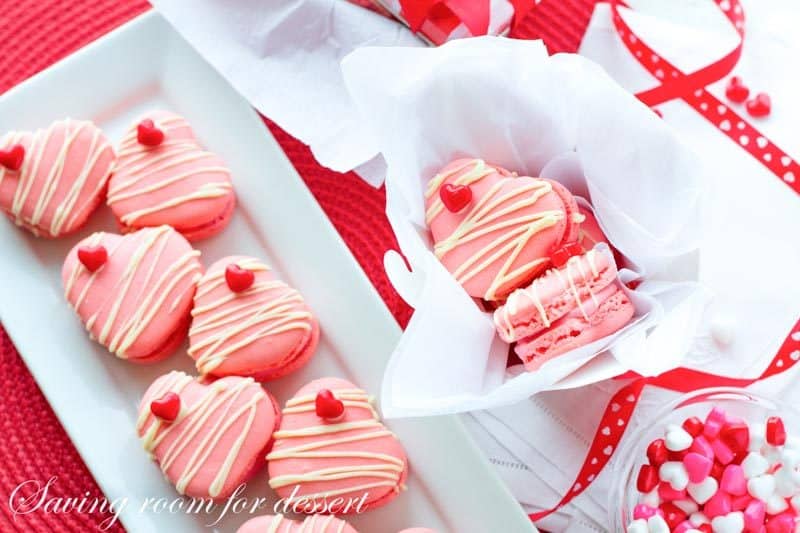 Raspberry Macarons - simple heart shaped macarons using the Italian method, with tips, tricks and how-to instructions for the best cookies. Filled with a fresh raspberry buttercream and topped with a drizzle of white chocolate. Great for Valentine's Day! www.savingdessert.com 