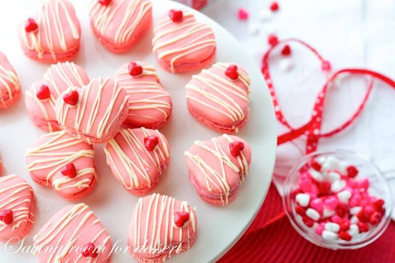 Raspberry Macarons - simple heart shaped macarons using the Italian method, with tips, tricks and how-to instructions for the best cookies. Filled with a fresh raspberry buttercream and topped with a drizzle of white chocolate. Great for Valentine's Day! www.savingdessert.com 