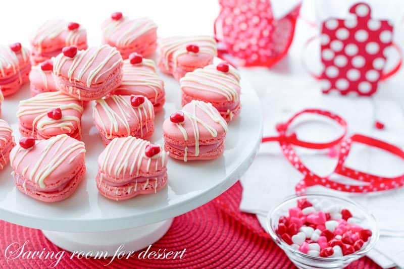 Raspberry Macarons - simple heart shaped macarons using the Italian method, with tips, tricks and how-to instructions for the best cookies. Filled with a fresh raspberry buttercream and topped with a drizzle of white chocolate. Great for Valentine's Day! www.savingdessert.com 