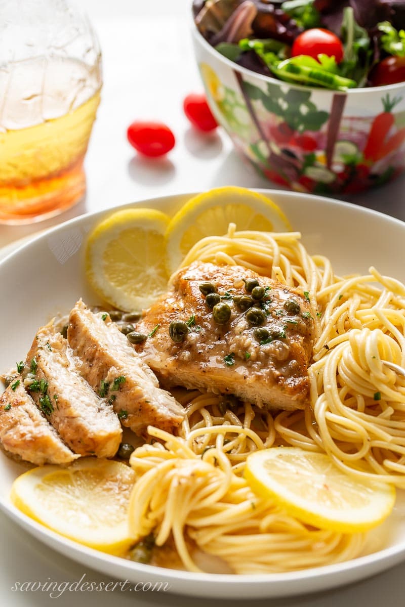 A bowl of spaghetti topped with a sliced chicken breast