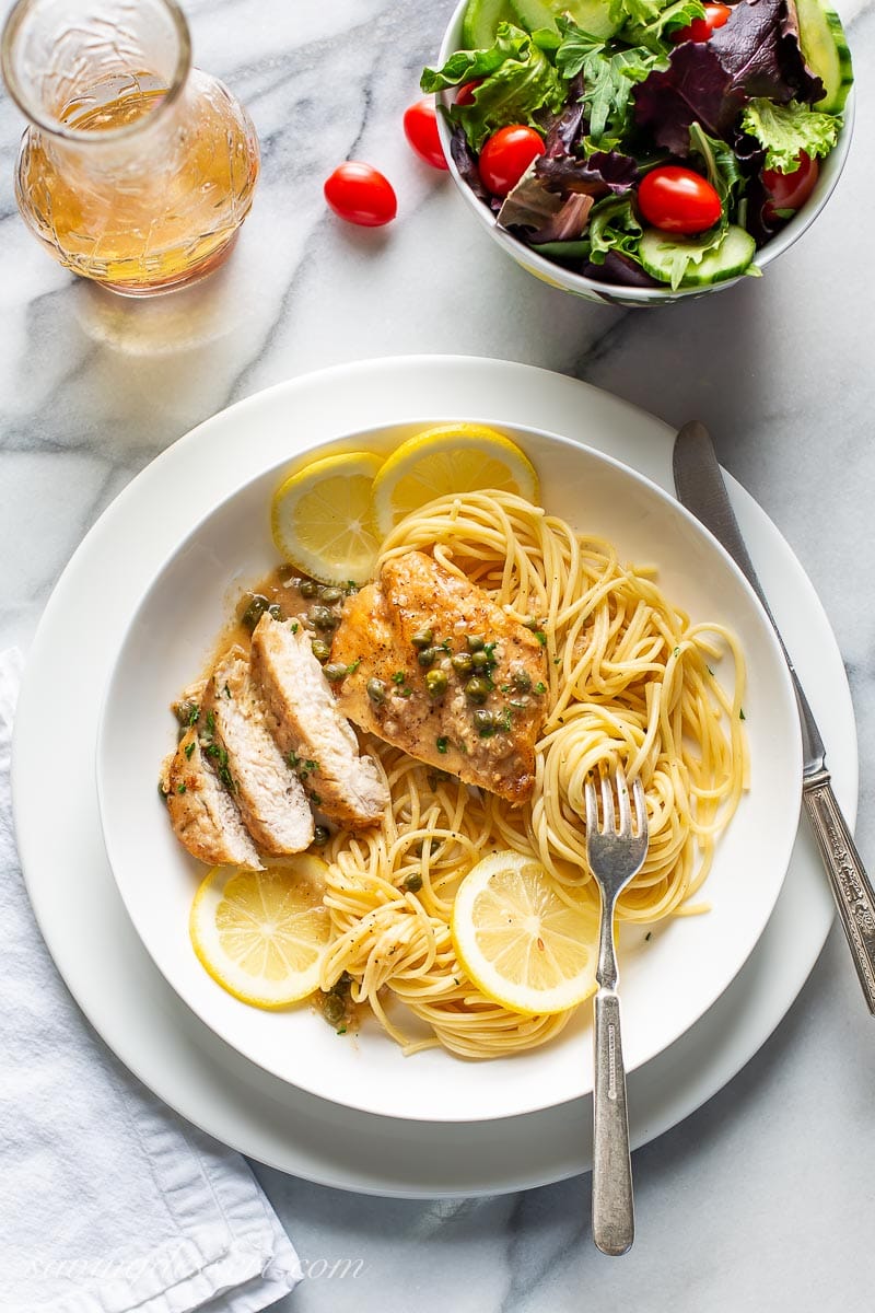 A plate with chicken, spaghetti and a salad