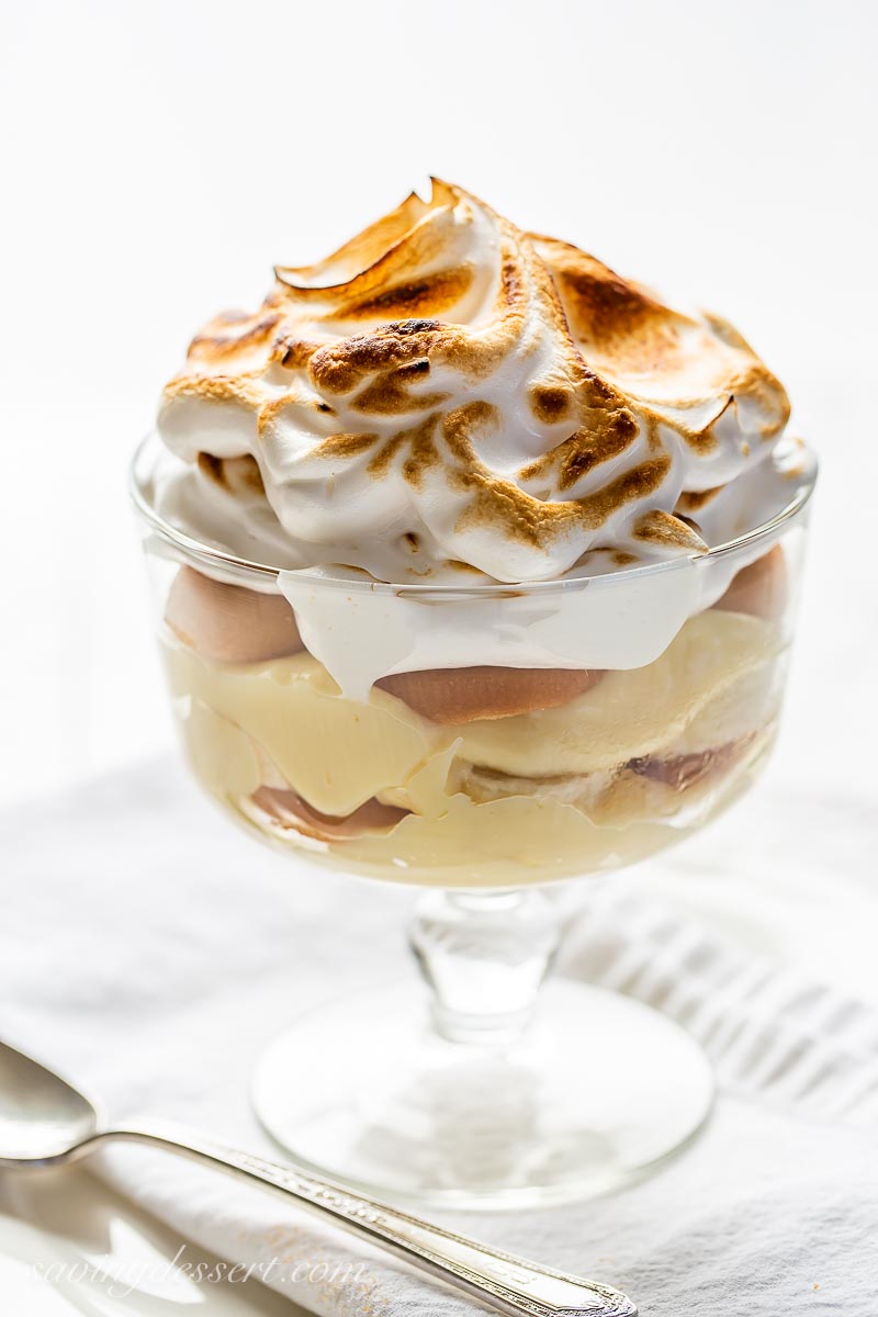 A mini clear dessert dish filled with vanilla pudding, vanilla wafers, bananas and a swirled toasted meringue