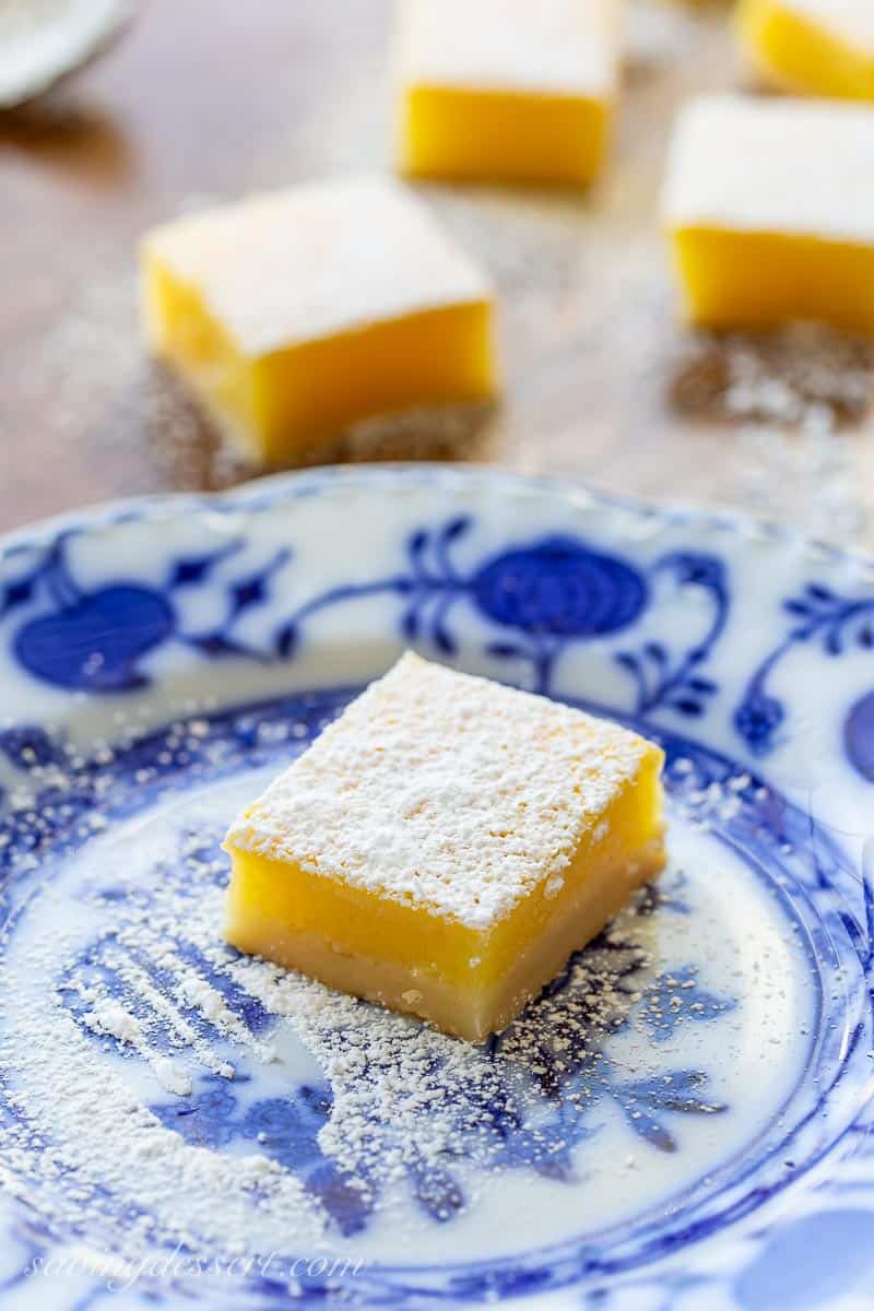 A lemon bar dusted with powdered sugar on a blue plate 