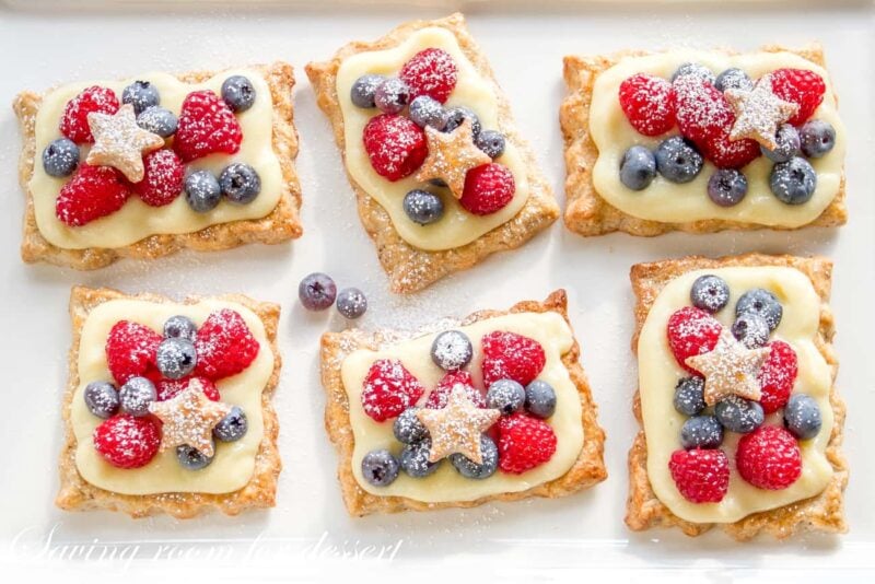 Individual pastry tarts with vanilla cream topped with fresh berries and star cutouts