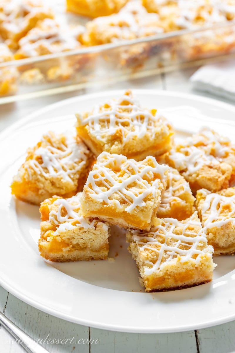 A plate of fresh peach crumb bars drizzled with icing