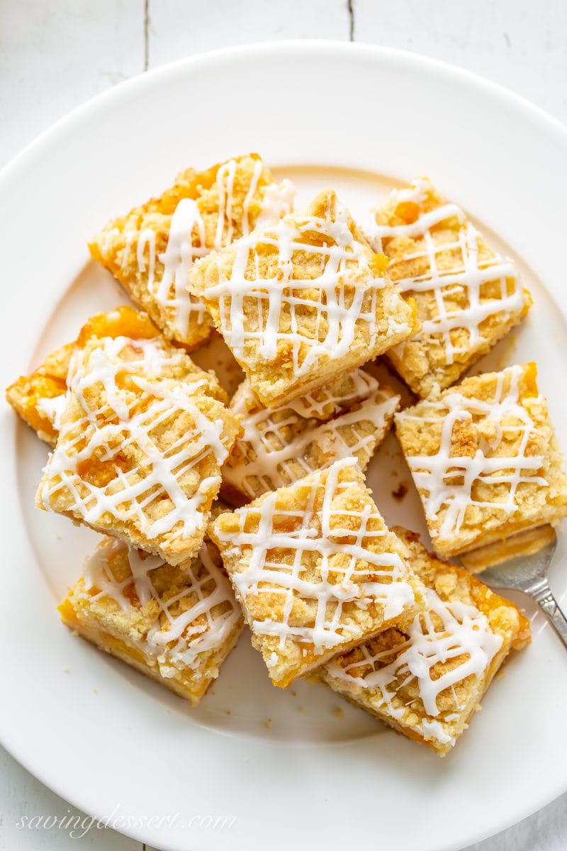 A plate filled with fresh peach crumb bars topped with a drizzled icing