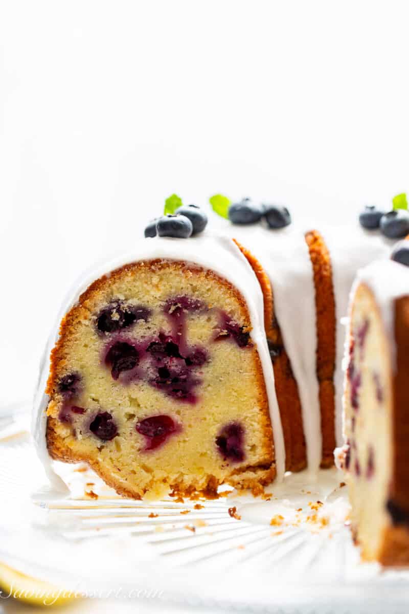 A side view of a sliced blueberry pound cake drizzled with icing.
