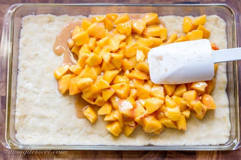 Fresh diced peaches spread over a crumb crust in a baking dish