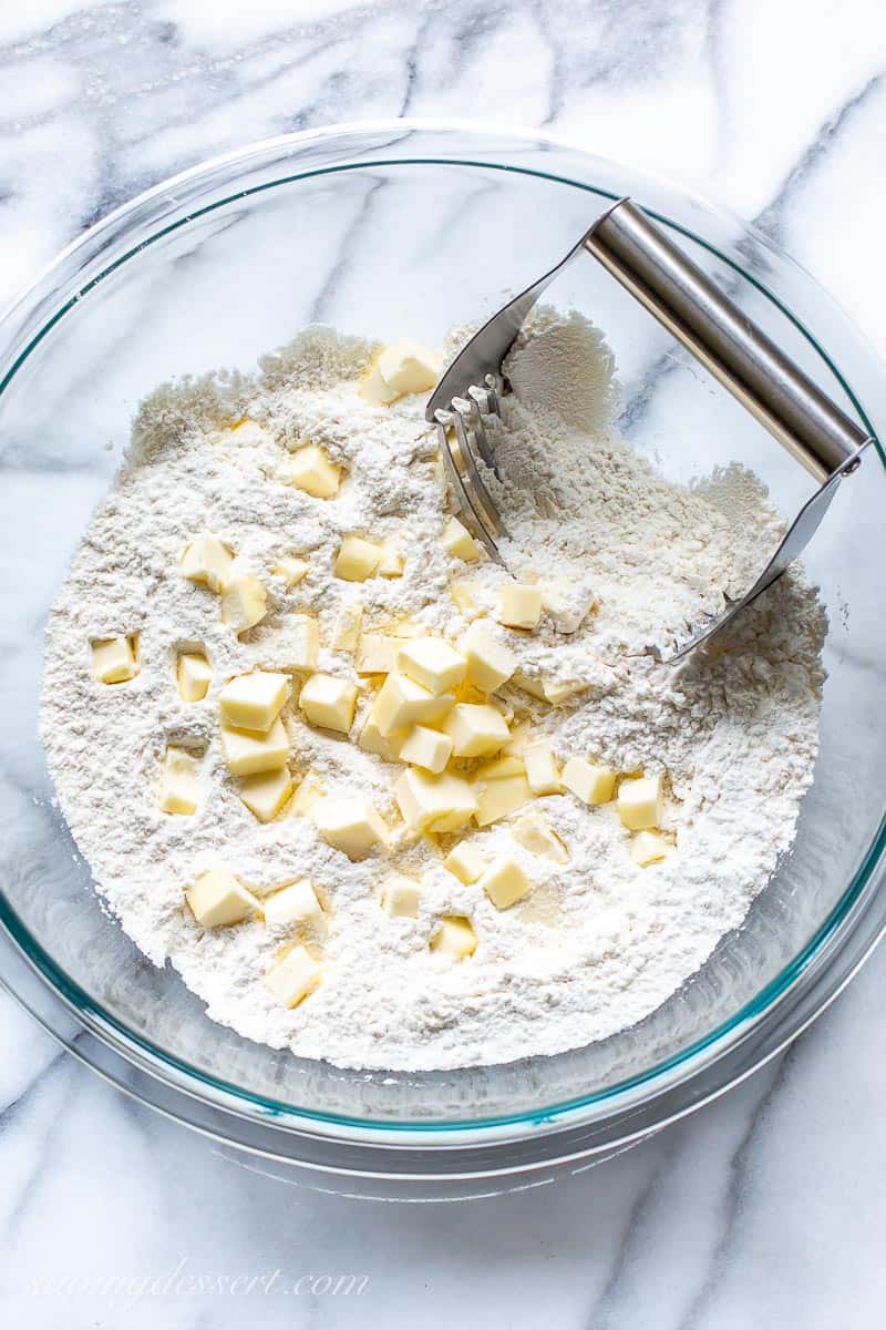 A bowl of flour with chunks of butter
