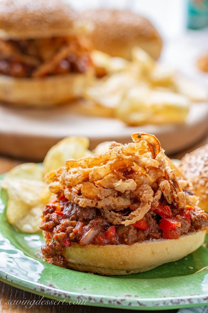 a Sloppy Joe sandwich piled high with juicy meat, red bell pepper and topped with crispy fried onions