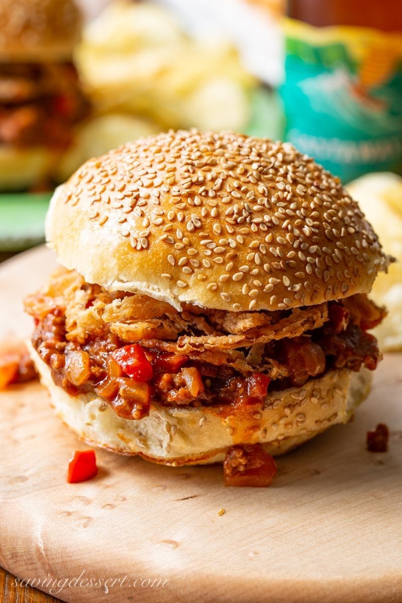 A Sloppy Joe sandwich with onions, red peppers and ground beef topped with crispy onions and a sesame seed bun
