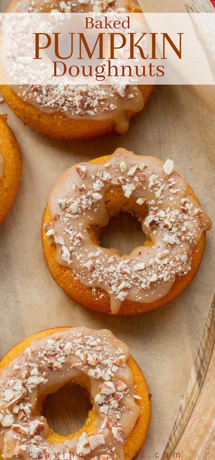 A tray of baked pumpkin doughnuts with caramel icing and chopped nuts