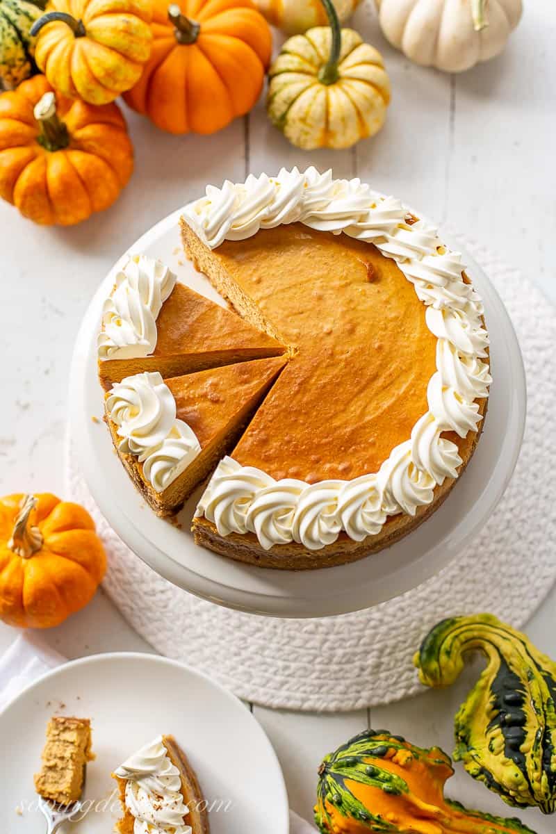 Overhead view of a table covered with pumpkins and a pumpkin spice cheesecake