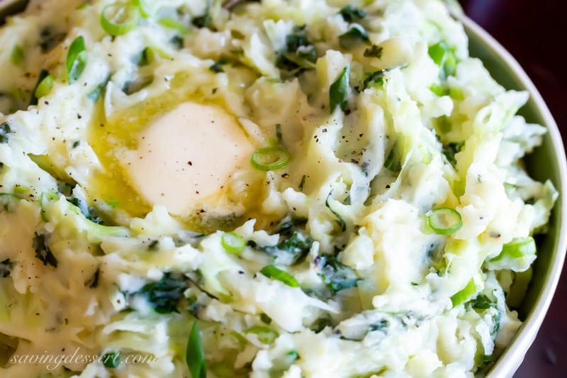 A close up of a bowl of colcannon with butter and scallions