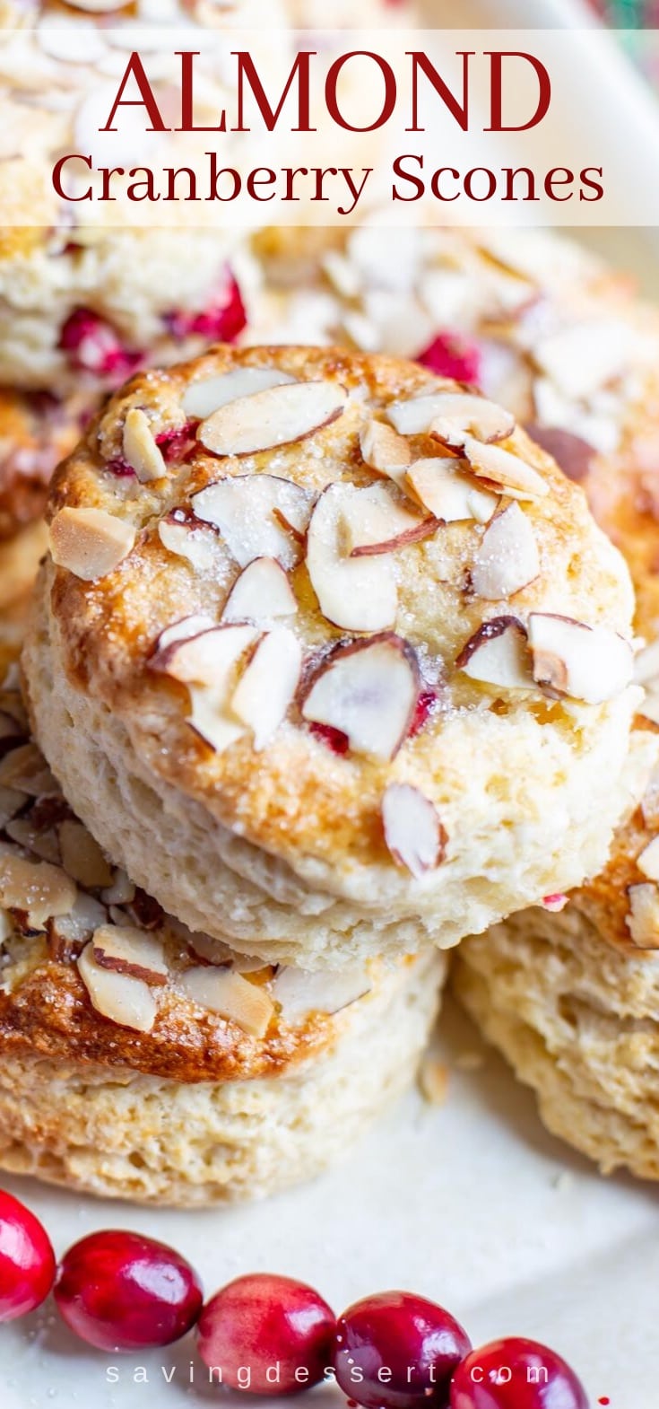 A close up of an almond cranberry scone topped with sliced almonds and coarse sugar