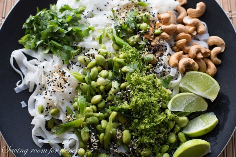 Rice Noodles with edamame and cashews - Sliced green onions and hot peppers are sautéed then tossed with a dressing of rice vinegar and sesame oil.  Add blanched edamame, sesame seeds, roasted unsalted cashews, garnish with chopped cilantro and lime zest then toss it all together with rice noodles and a squeeze of lime juice.  www.savingdessert.com