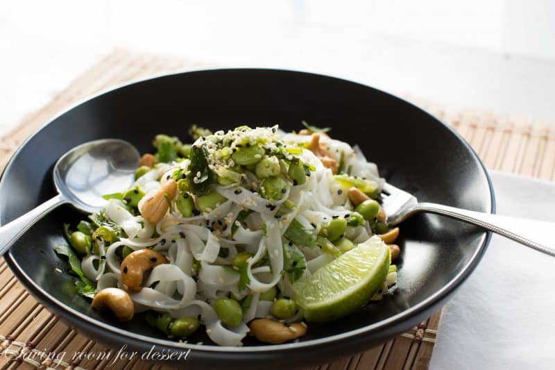 Rice Noodles with edamame and cashews - Sliced green onions and hot peppers are sautéed then tossed with a dressing of rice vinegar and sesame oil.  Add blanched edamame, sesame seeds, roasted unsalted cashews, garnish with chopped cilantro and lime zest then toss it all together with rice noodles and a squeeze of lime juice.  www.savingdessert.com