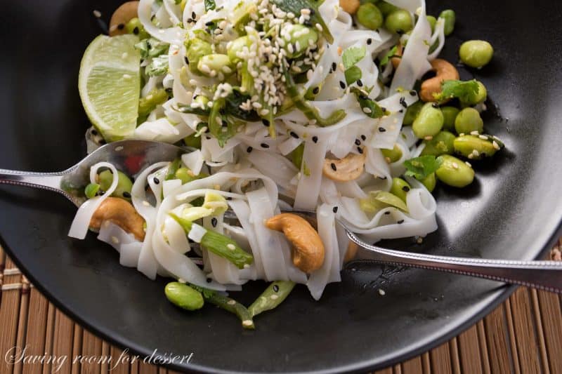 Rice Noodles with edamame and cashews - Sliced green onions and hot peppers are sautéed then tossed with a dressing of rice vinegar and sesame oil.  Add blanched edamame, sesame seeds, roasted unsalted cashews, garnish with chopped cilantro and lime zest then toss it all together with rice noodles and a squeeze of lime juice.  www.savingdessert.com