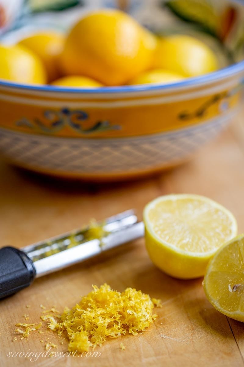 a bowl of lemons and lemon zest on a cutting board