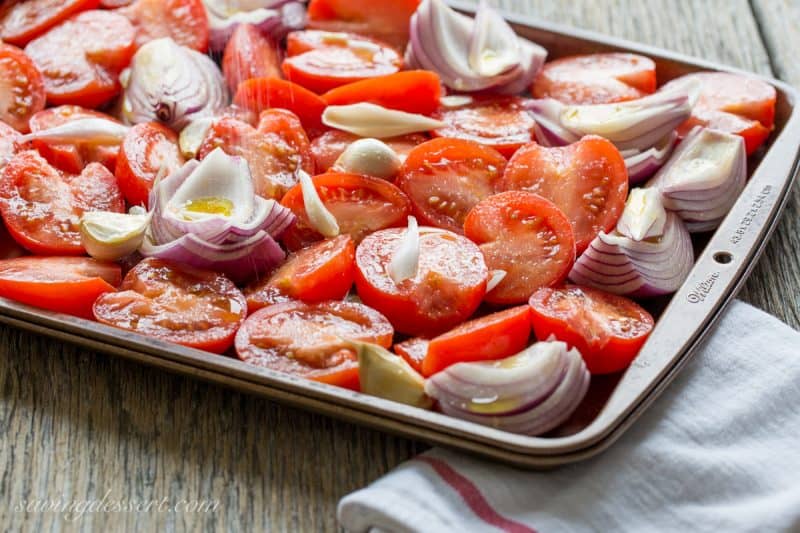 A pan of tomatoes, onion and garlic drizzled with olive oil