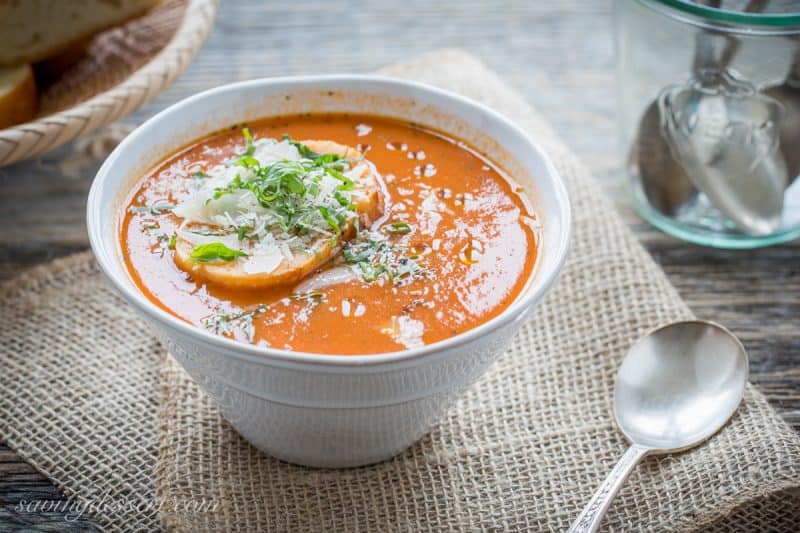 Roasted Tomato Basil Soup in a bowl topped with fresh basil and cheese