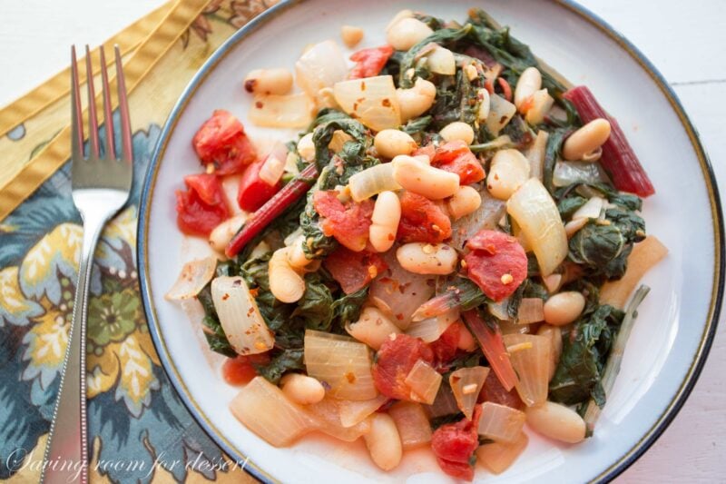 A plate with Swiss Chard, white bean, onion, and tomato stew with crushed red pepper