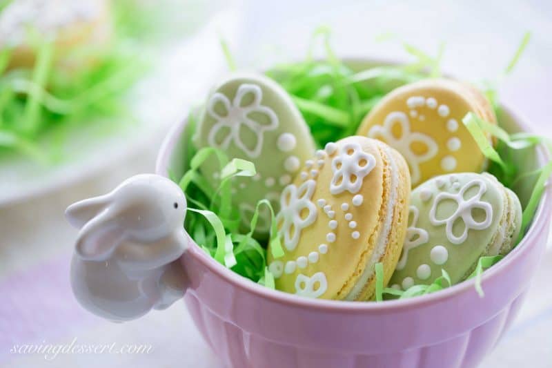 Easter egg macarons in yellow and green decorated with royal icing