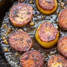 A cast iron skillet with crispy potatoes with garlic and thyme