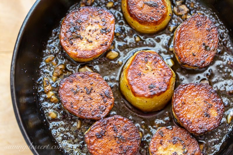 A cast iron skillet with crispy potatoes with garlic and thyme