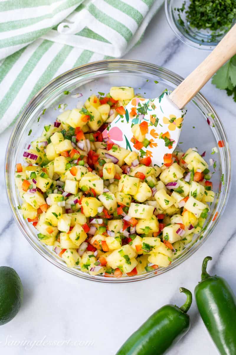 A mixing bowl with fresh made pineapple salsa with red and green peppers.