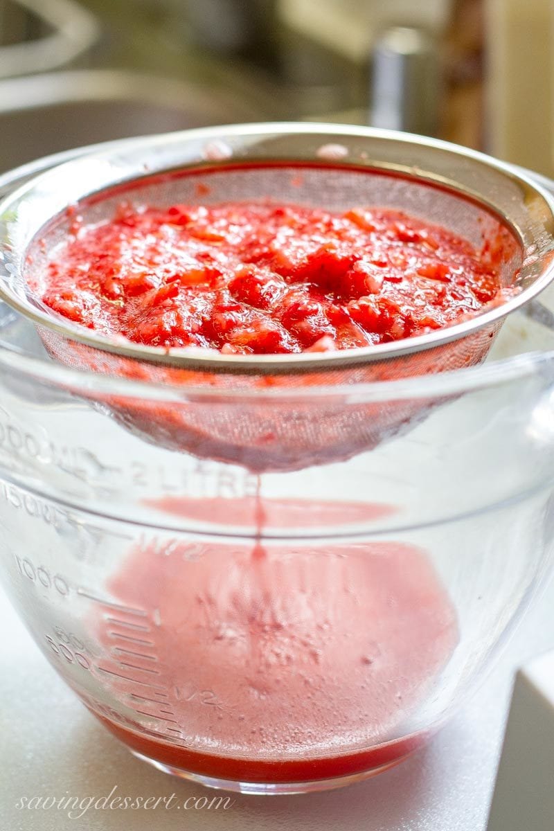 draining chopped strawberries in a sieve set over a bowl