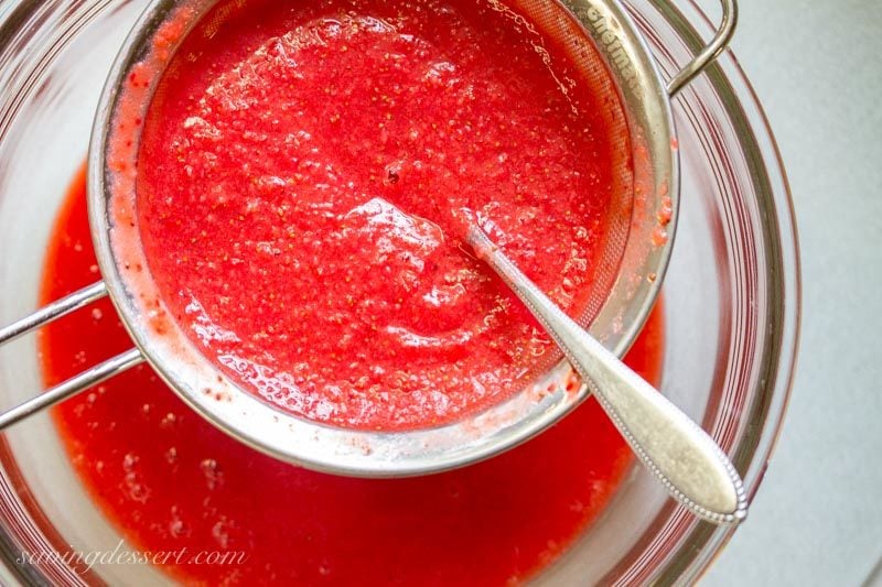 strawberry puree in a sieve set over a bowl