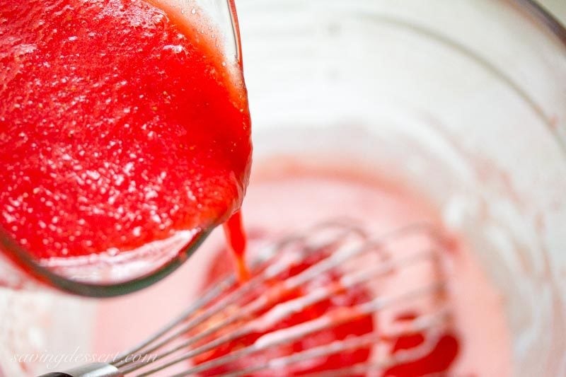 strawberry puree being poured into a mixing bowl with a whisk