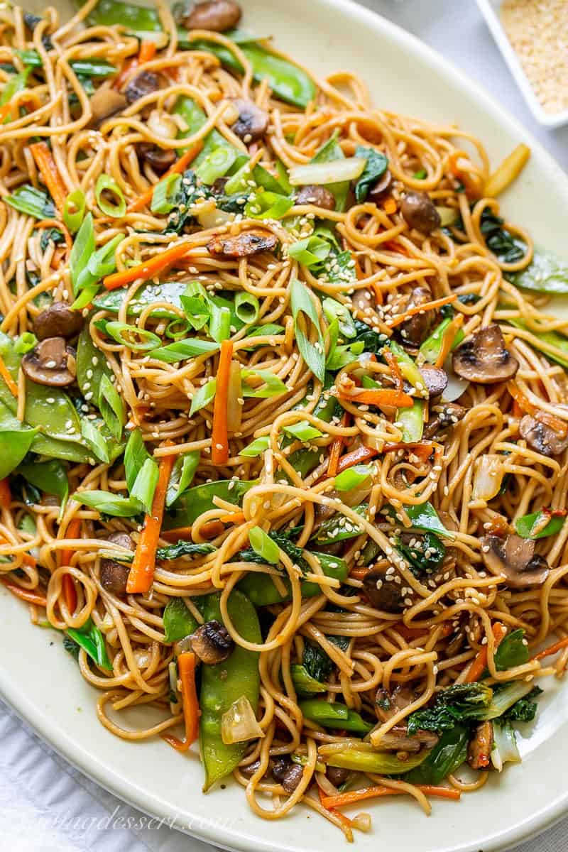 Closeup of a platter of veggie lo mein topped with sliced green onions