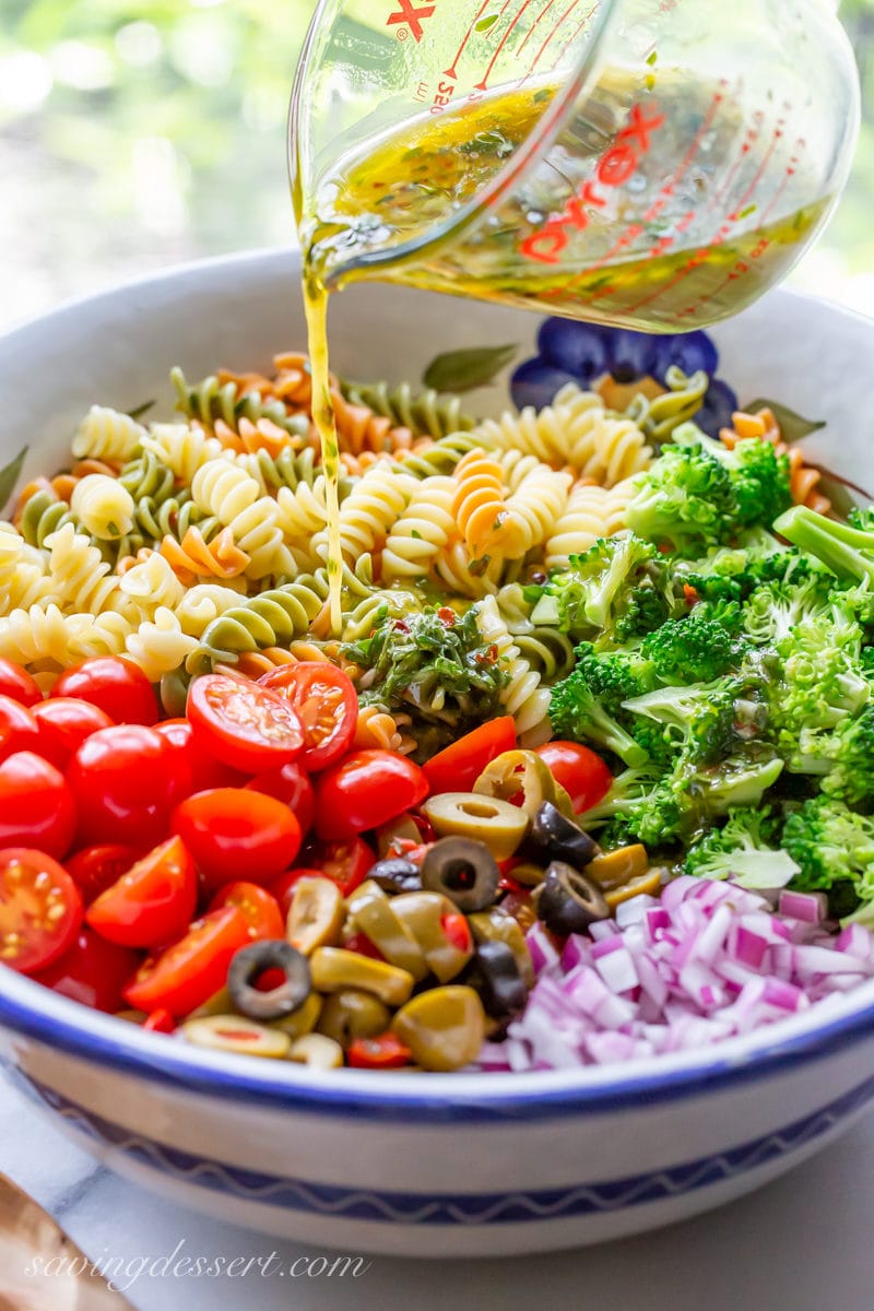 A bowl of cooked Rotini spiral noodles, broccoli, tomatoes, olives and red onion drizzled with a fresh zesty Italian dressing.