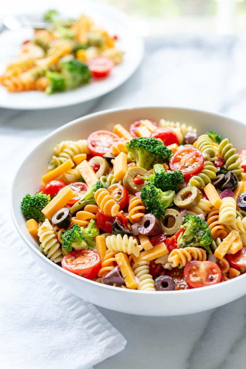 A bowl of pasta salad with broccoli, tomatoes, cheese and olives