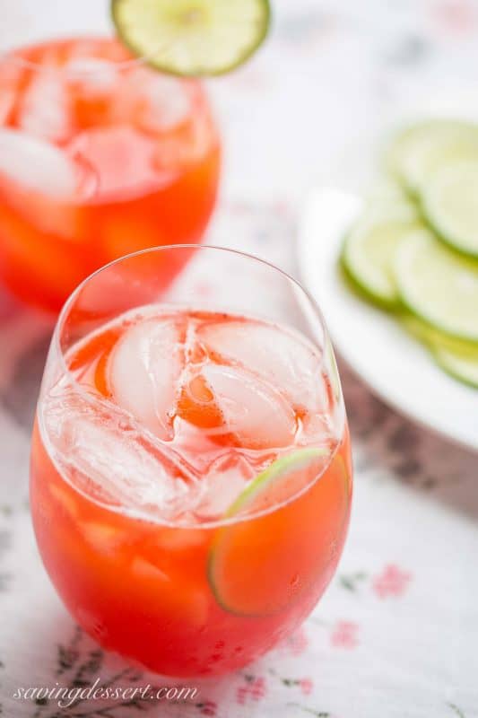 A close up of two glasses of strawberry agua fresca garnished with limes