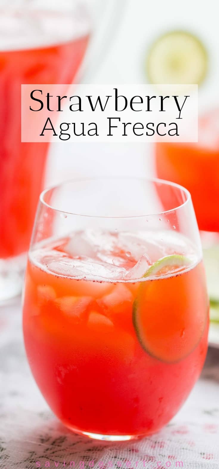 A glass of Strawberry Agua Fresca with ice and lime