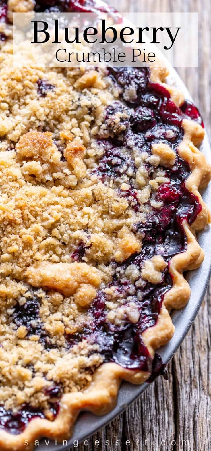 A close up of a blueberry crumble pie with juices overflowing the edges of the crust and pan