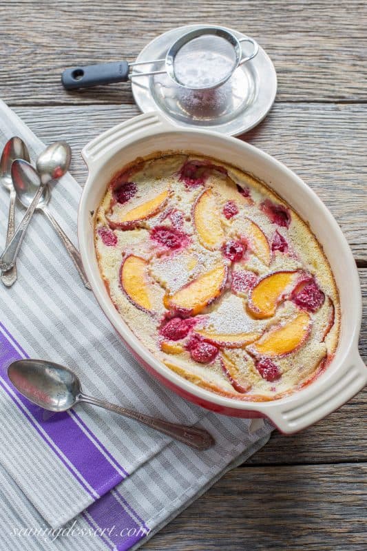 Raspberry Peach Clafoutis (pronounced klafuti) is a traditional French dessert made with seasonal fresh fruit, covered in a thick custard-like batter, then baked. It is often served warm with a dusting of confectioners' sugar. 