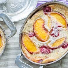 An overhead view of a small casserole dish filled with a custardy peach and raspberry dessert