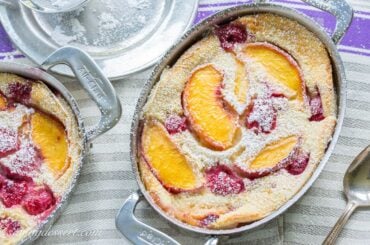 An overhead view of a small casserole dish filled with a custardy peach and raspberry dessert