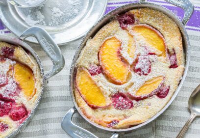 An overhead view of a small casserole dish filled with a custardy peach and raspberry dessert