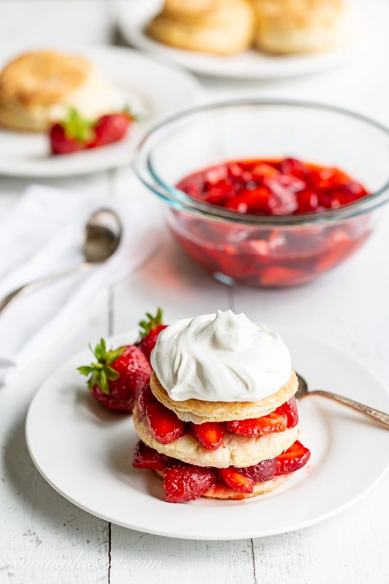 A simple scone topped with fresh sliced strawberries and whipped cream